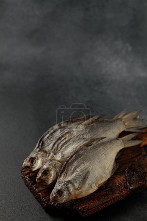 Dried bream fish on a cutting board on a black background