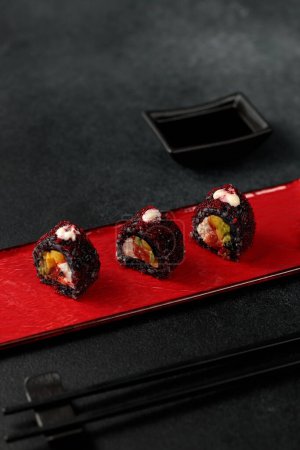 Foto de Japanese food: sushi, Roll with cuttlefish ink, mango, salmon, tobiko caviar, avocado. Black background - Imagen libre de derechos