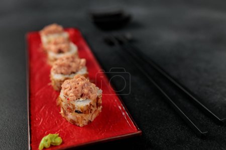 Japanisches Essen: Sushi, Shiitaki-Rolle mit Thunfisch, Avocado, Philadelphia, Kimchi, Thunfischflocken Schwarzer Hintergrund