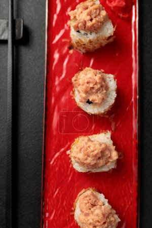 Japanisches Essen: Sushi, Shiitaki-Rolle mit Thunfisch, Avocado, Philadelphia, Kimchi, Thunfischflocken Schwarzer Hintergrund