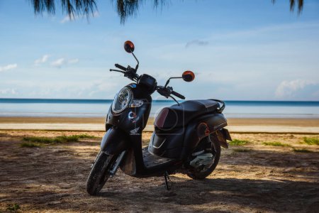 Photo for Black Honda Scoopy motorbike on a tropical beach in Ko Lanta, Krabi, Thailand. November 30, 2022. - Royalty Free Image