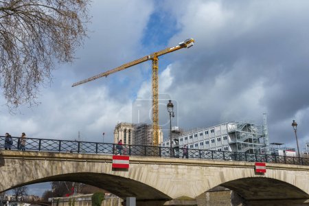 Foto de Pont de l 'Archeveche (Puente del Arzobispo) con el sitio de construcción de Notre-Dame en el fondo. París, Francia. 24 de marzo de 2023. - Imagen libre de derechos