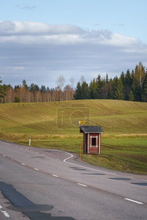 Foto de Parada de autobús en el campo finlandés con refugio de madera roja y campos verdes en el fondo - Imagen libre de derechos