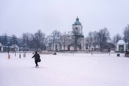 Photo for One person walking in Market Square in front of Hameenlinna church in winter. Finland, February 23, 2023. - Royalty Free Image