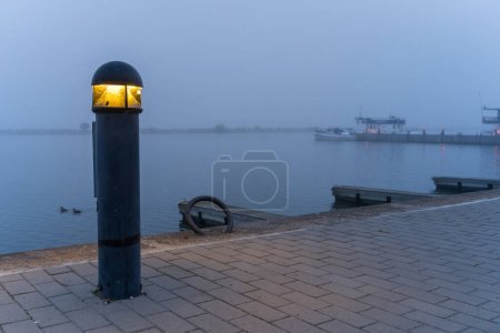 Lumière de borne dans un port par une matinée brumeuse bleue