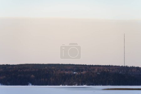 Frozen lake landscape with a tall radio tower in the distance. Lahti, Finland.