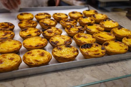 Traditional Portuguese Pastel De Nata pastries on pastry shop counter in Lisbon