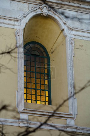 Ventana barroca con luz amarilla radiante en una elegante fachada europea