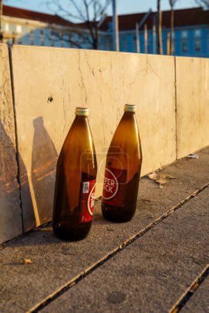 Photo for Two empty beer bottles on a street by a stone wall in sunset. Lisbon, Portugal. February 2, 2024. - Royalty Free Image