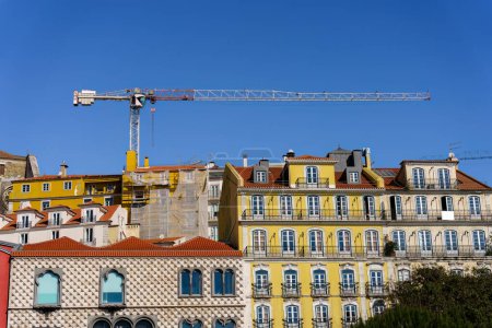Turmkran über historischen Gebäudefassaden in Lissabon, Portugal bei klarem Himmel