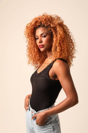 Fashionable young beautiful woman with afro hairstyle posing on the black wall. High quality photo.