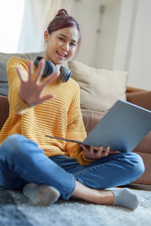 Portrait of a young Asian woman using a computer on the sofa. Poster 617705838