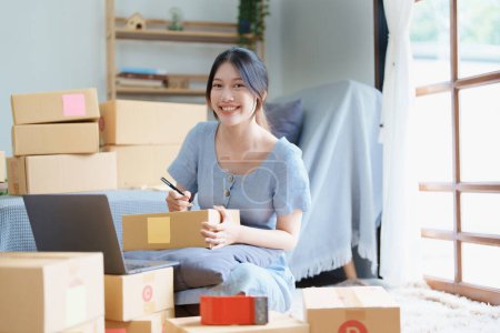 Photo for Starting small business entrepreneur of independent young Asian woman online seller is using computer and taking orders to pack products for delivery to customers. SME delivery concept. - Royalty Free Image