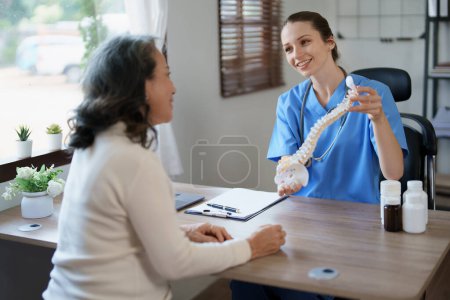 Foto de Retrato de una doctora hablando con un paciente anciano sobre el deterioro del disco herniado por largas horas de trabajo - Imagen libre de derechos