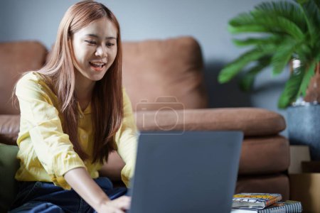 Portrait of a beautiful Asian teenage girl using a computer. Poster 648160194