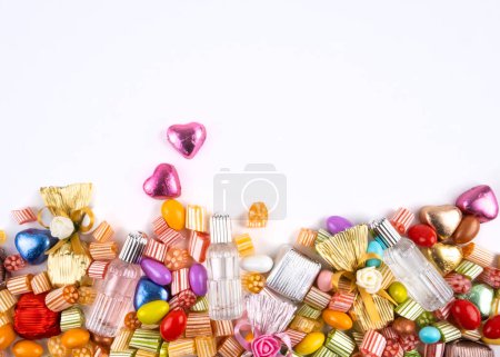 Various sweet assortment, top view half full various sweet assortment. Isolated white background, copy space. Candy, wrapped chocolate, hearth shape, almond, cologne mixed group of sugar. 