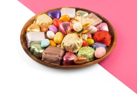 Placa de azúcar de colores, cerca de la imagen de la placa de azúcar de colores. Dulces mezclados, chocolate de lujo envuelto, dragee almendra, dulces duros. Fondo rosa y blanco aislado. Ramadán tradicional turco.