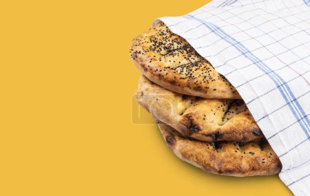 Ramadan pita called in Turkish Ramazan pidesi. Eye view concept image of round breads isolated on yellow background. Copy space. Traditional Turk pastry for holy islam month.