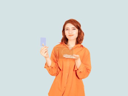 Sad woman holding credit bank card, portrait of young caucasian red bob hair sad woman holding credit bank card. Thoughtful female stressed about her debts. Open palm bored face expression.