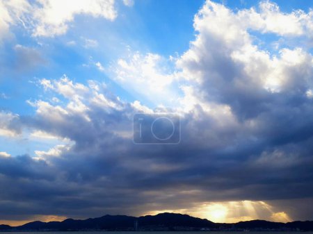 Photo for Sunset light and mountain silhouettes pouring through the clouds. - Royalty Free Image