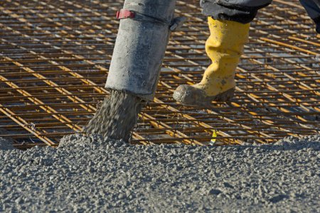 Photo for Construction worker pours concrete on rebar using concrete pump - Royalty Free Image