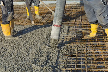 Construction worker pours concrete on rebar using concrete pump