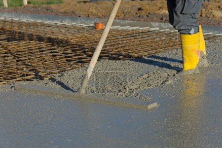 Construction worker smooths concrete of a floor slab