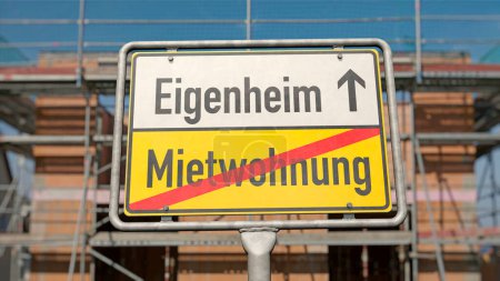 Foto de Construir su propia casa en lugar de vivir en un apartamento alquilado - Cartel con el nombre del lugar con las palabras alemanas "Mietwohnung" (piso alquilado) y "Eigenheim" (granja) - Imagen libre de derechos