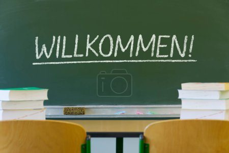 pizarra en el aula con tiza alemana escribiendo "Willkommen" (bienvenida)
