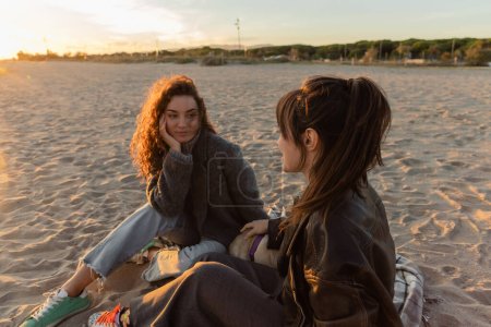Amis parlant près de chiot chiot sur la plage de sable en Espagne 