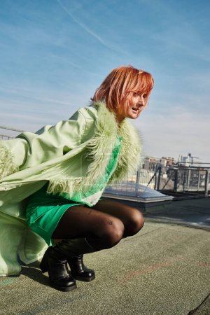 Téléchargez les photos : Joyeuse voyageuse en tenue décontractée élégante assise sur des hanches sur la terrasse du toit à Vienne - en image libre de droit