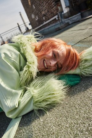 Städtereise, sorglos gestylte Frau liegt auf Dachterrasse und blickt in Wien in die Kamera