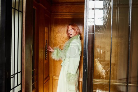trendy woman looking at camera from vintage elevator in residence building in Vienna, Austria