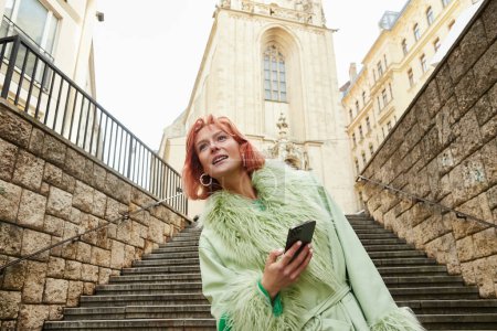 mode de vie de voyage, femme branchée avec téléphone portable regardant loin sur la rue urbaine à Vienne, Autriche