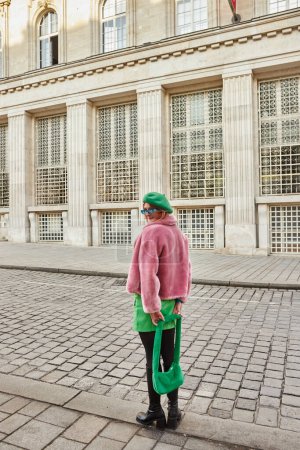 Téléchargez les photos : Femme élégante en fausse fourrure veste et lunettes de soleil regardant la caméra tout en marchant dans la rue à Vienne - en image libre de droit