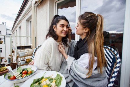 intimate and happy moment of loving lesbian couple having breakfast on balcony, lgbt concept
