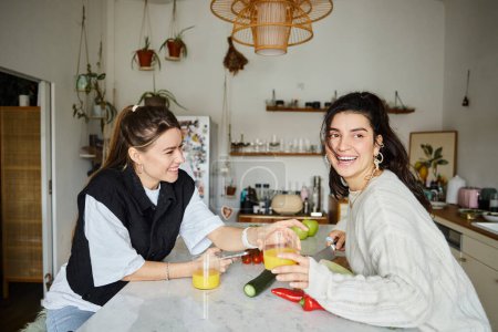 glücklicher und gemütlicher moment eines jungen lesbischen paares, das zeit in der küche verbringt und salat kocht, lgbt