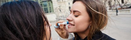 love and affection of lesbian woman applies lip balm on lips of her girlfriend, banner