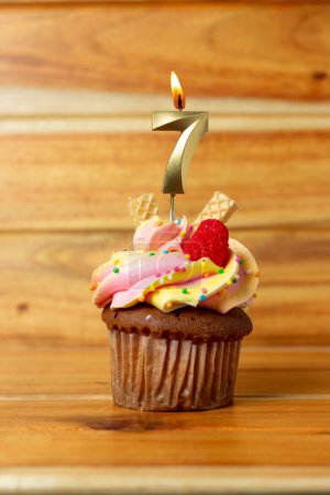 Foto de Vela de cumpleaños dorada sobre fondo de madera - Magdalena de cumpleaños con vela numerada - Imagen libre de derechos