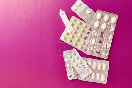 Foto de Packets with different pills and container with liquid on pink background. - Imagen libre de derechos
