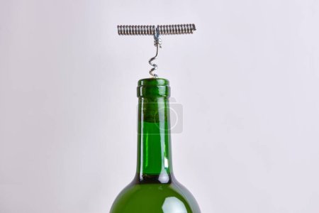 Téléchargez les photos : Un tire-bouchon métallique est vissé dans le bouchon de la bouteille de vin. - en image libre de droit