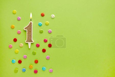 Numéro 1 sur un fond vert pastel avec des émoticônes colorées. Joyeux anniversaire bougies. Le concept de célébrer un anniversaire, un anniversaire, une date importante, une fête. Espace de copie. bannière