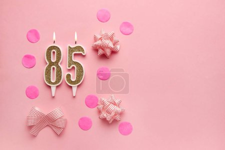 Number 85 on pastel pink background with festive decor. Happy birthday candles. The concept of celebrating a birthday, anniversary, important date, holiday. Copy space. banner