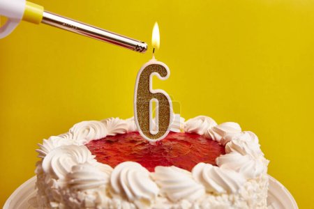 Photo for A candle in the form of the number 6, stuck in a festive cake, is lit. Celebrating a birthday or a landmark event. The climax of the celebration. - Royalty Free Image