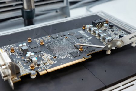 A video card with a freshly soldered GPU chip using an infrared soldering station. Maintenance and repair of computer equipment.