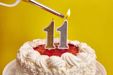 Photo for A candle in the form of the number 11, stuck in a holiday cake, is lit. Celebrating a birthday or a landmark event. The climax of the celebration. - Royalty Free Image