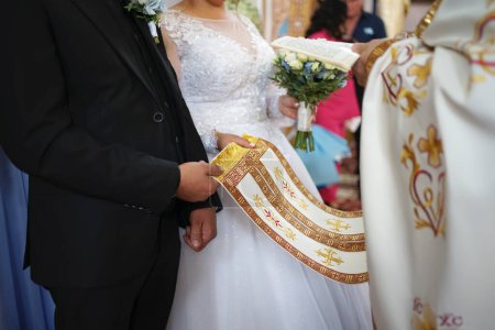 Photo for During a church wedding, the bride and groom hold onto the epitrachyl. Symbolizes the blessed gifts of the priest as a spiritual person. - Royalty Free Image