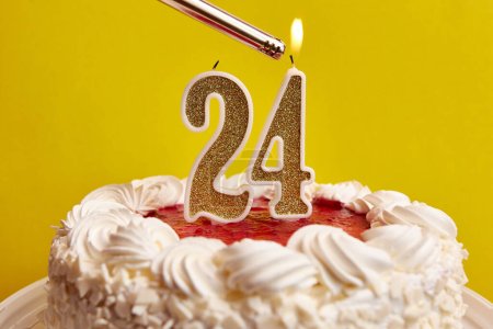 Photo for A candle in the form of the number 24, stuck in a holiday cake, is lit. Celebrating a birthday or a landmark event. The climax of the celebration. - Royalty Free Image