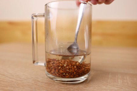 Photo for To prepare a therapeutic decoction, flax seeds are shaken in a glass of boiling water. - Royalty Free Image