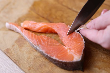 The skin is cut from a piece of salmon. Cooking salmon fish.